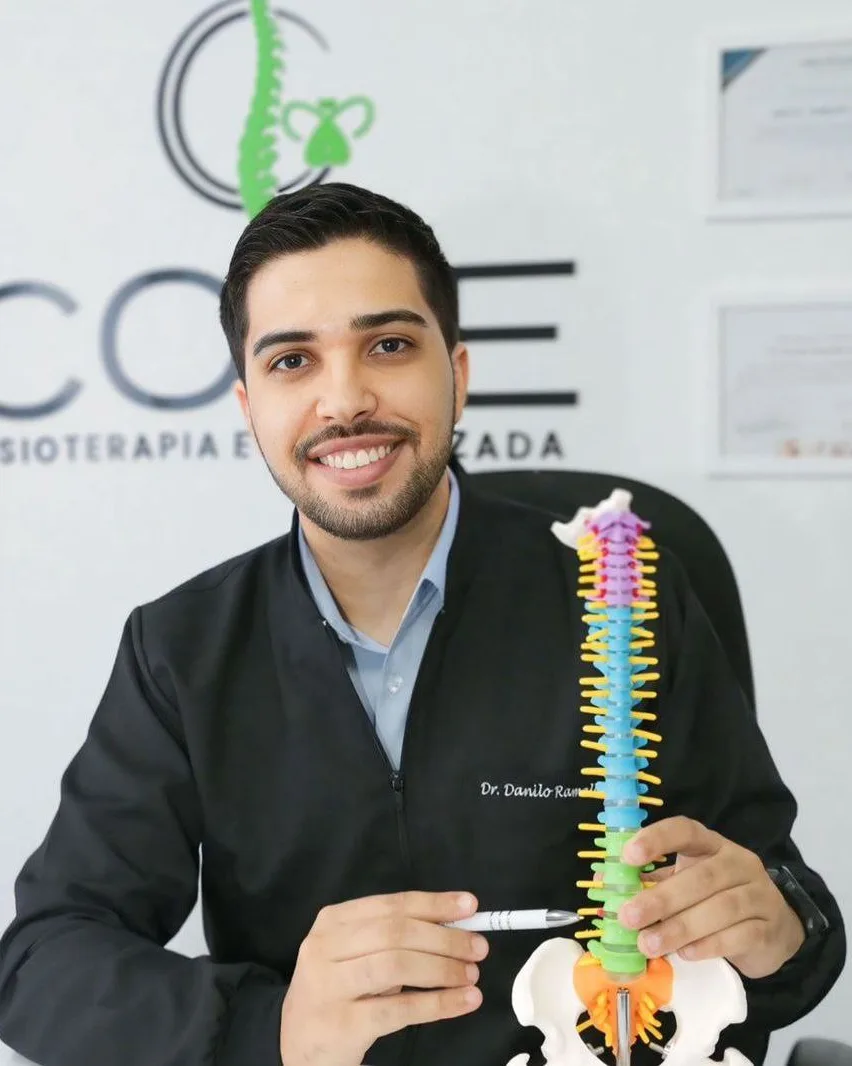 Dr. Danilo Ramalho, fisioterapeuta especialista em coluna, segurando um modelo de coluna vertebral